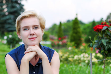 Blue-eyed blonde woman in blue dress in the garden on a summer dayの写真素材