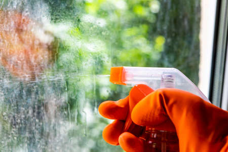 A cleaning service worker washes the window from dust and dirt on a dirty window. Close-up of cleaning windowsの写真素材