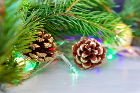 Spruce branch with pine cones and lights of luminous garland, christmas home decorの写真素材