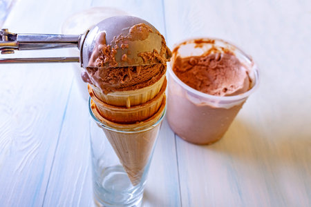 Ice cream set - waffle cones, chocolate ice cream. Ice cream is put into a cone with a spoon on a...