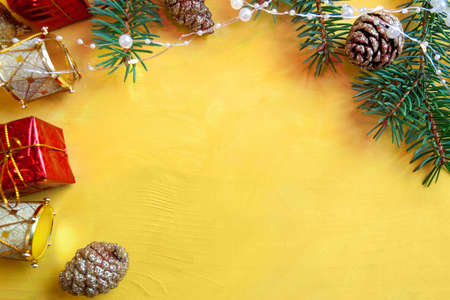 New Years decor on a yellow table - fir branches, cones, garlands and Christmas toysの写真素材