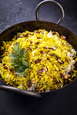 Indian vegetarian biryani with nuts and raisins as close-up in a korai の写真素材