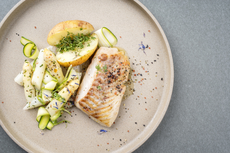 Modern German fried cod fish filet with white asparagus tips and roast potatoes as top view on a plate with copy space rightの写真素材