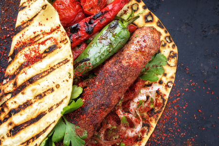 Traditional Adana Kebap with tomato and salad on a flatbread with copy space rightの写真素材