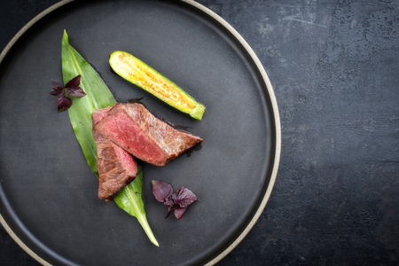 Traditional barbecue dry aged sliced fillet steak with wild garlic and baby zucchini as top view on a plate with copy space rightの写真素材