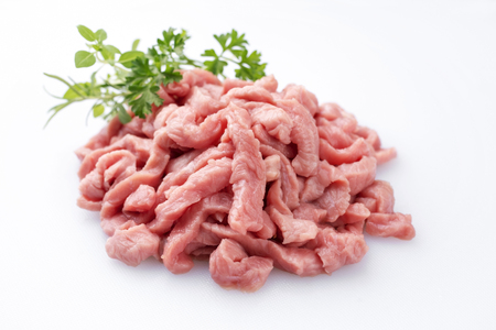 Raw veal strips for traditional Swiss zï¿½rcher geschnetzeltes with herbs as closeup on white background ï¿½ isolatedの写真素材