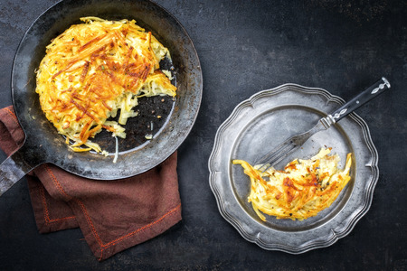 Traditional Swiss rosti as side dish with leek as top view in a frying pan and a pewter plateの写真素材