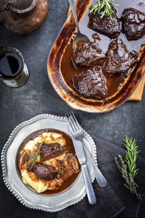 Traditional German braised veal cheeks in brown sauce with mashed potatoes as top view on a pewter plateの写真素材