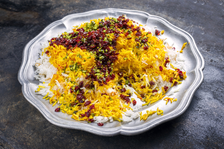Traditional Iranian steamed saffron rice with berberis and pistachios as closeup on a pewter plateの写真素材