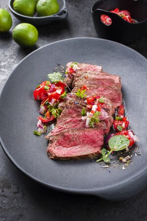 Traditional South American barbecue wagyu roast beef sliced with pico de gallo and salsa verde garnished as closeup in a modern design plateの写真素材