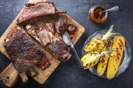 Barbecue sliced chuck beef ribs with hot rub with pineapple and corn as top view sliced on a wooden cutting board の写真素材
