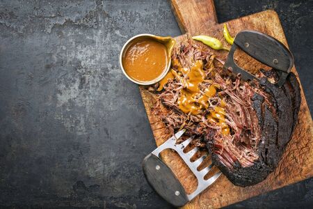 Traditional barbecue wagyu pulled beef with spicy sauce as top view on a rustic cutting board with copy space leftの写真素材