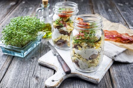 Brotzeit im Glas â traditional Bavarian snack with ham, eggs and black bread in a glass as closeup on a wooden boardの写真素材