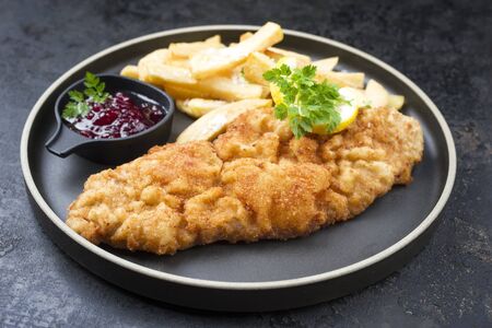 Fried Wiener schnitzel from veal topside with French fries and cranberry sauce as closeup modern design plateの写真素材