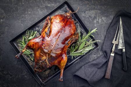 Traditional roasted stuffed Christmas Peking duck with herbs as top view on a rustic board with copy spaceの写真素材