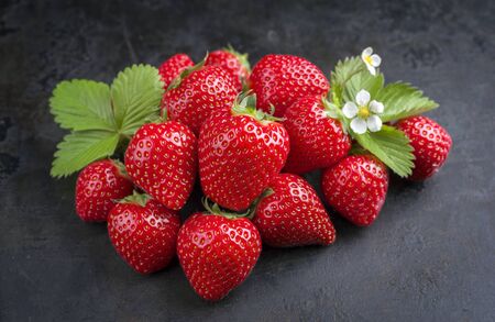 Fresh ripe strawberries offered as closeup on black rustic board as background の写真素材