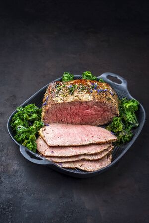 Traditional Commonwealth Sunday roast with sliced cold cuts roast beef with kalette and herbs as closeup on a modern design panの写真素材