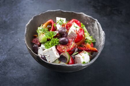 Traditional Greek farmers salad with tomatoes, olives and feta cheese offered as closeup in a rustic modern design bowl の写真素材