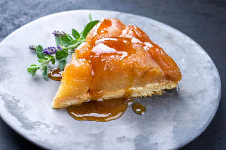 Traditional French tart tatin with apples and vanilla offered as close-up on a modern design plate with rustic backgroundの写真素材