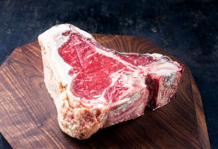 Raw dry aged wagyu t-bone beef steak offered as close-up on modern design wooden boardの写真素材