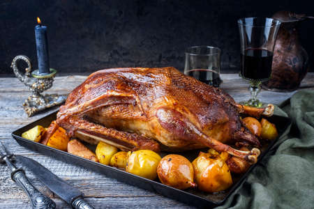 Traditional roasted stuffed Christmas goose with quinces and orange slices served as close-up on an old rustic trayの写真素材