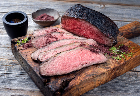 Traditional Commonwealth Sunday roast with sliced cold cuts roast beef with herbs and salt served as close-up on an old rustic wooden boardの写真素材
