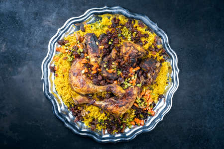 Traditional fried Arabic chicken majboos with chicken leg and jeweled rice served as top view in a rustic oriental trayの写真素材
