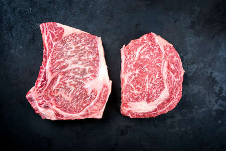 Two raw dry aged wagyu cutlet steak cut offered as close-up on black background with copy spaceの写真素材
