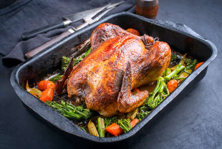 Traditional barbecue chicken with baby broccoli and carrots served as close-up in an old rustic metal trayの写真素材