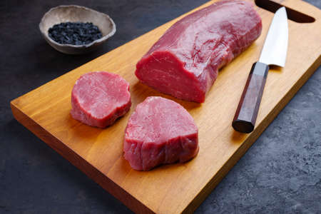 Traditional raw beef fillet steak natural with black salt as close-up on a modern design wooden boardの写真素材