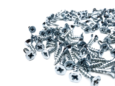 Chaotic scattered shiny screws on a white background. Furniture fittings for mounting.の写真素材