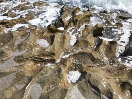 Stones by the sea of fancy shape and color. Foamy surf of the sea.の写真素材