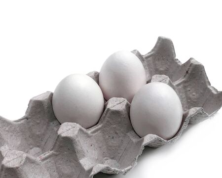 Three bird eggs in a cardboard tray on a white background with a light shadow. Normal food. View from above. Eco packaging.の写真素材