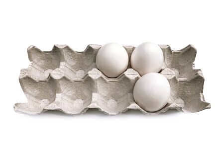 Three bird eggs in a cardboard tray on a white background with a light shadow. Normal food. View from above. Eco packaging.の写真素材