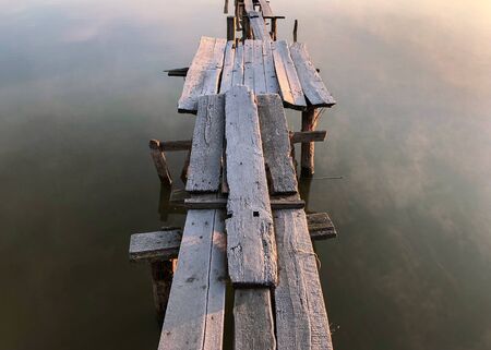 Wood masonry on the lake. Morning with light fog. Rotten pier on the shore of a calm reservoir.の写真素材