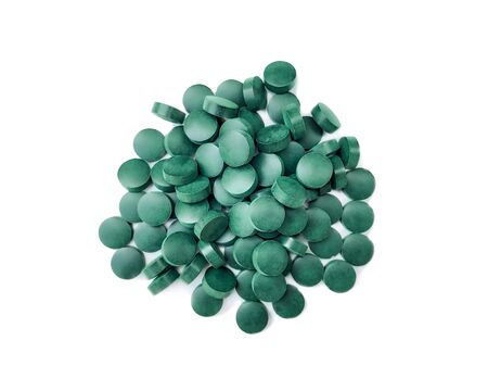Spirulina pills of blue-green algae on a white background with a light shadow. View from above.の写真素材