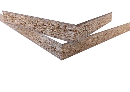 Wood chips and sawdust pressed into sheet material. On a white background with place for text. Uni color board. For the manufacture of cabinet furniture.の写真素材