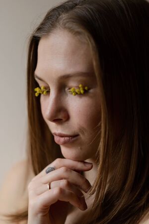 Portrait of a girl with mimosa flowers on eyelashesの写真素材