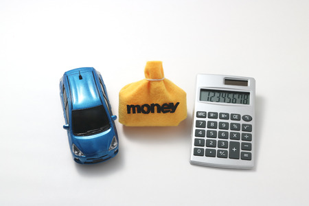 Toy car, money, and calculator on white background.の写真素材