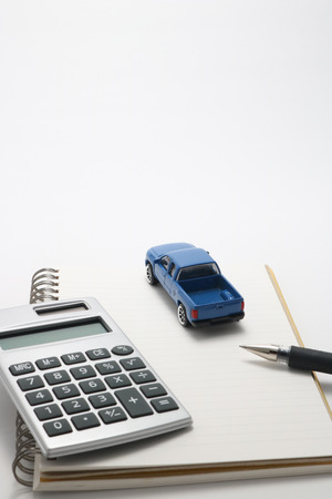 Toy car truck, calculator, notebook, and pen.の写真素材