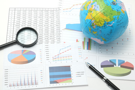 Globe, pen, business items, and business documents with numbers and charts. Concept of workplace of the businessman. Globe, pen, business items, and business documents with numbers and charts. Concept of workplace of the businessman.