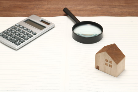 Miniature house, magnifying glass, calculator, pen and notebook. New house concept.の写真素材