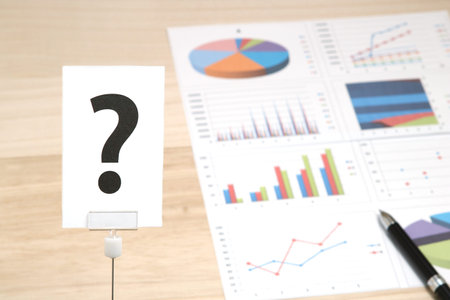 Big question mark on a piece of paper and business documents. Big question mark on a piece of paper and charts and graphs. Question concept.の写真素材