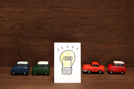Handwritten bulb illustration and miniature cars on wood. Electric car concept.の写真素材