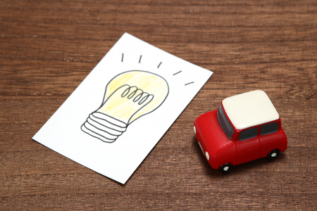 Hndwritten bulb illustrtion and miniture car on wood. Electric vehicle concept.の写真素材