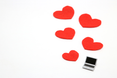 Miniature laptop and some red hearts on white background. Concept of love using a personal computer.の写真素材