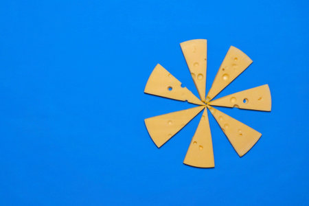 Slices of cheese on a blue background. Top view