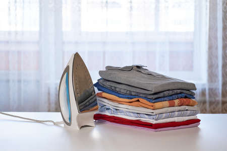 Iron and a stack of clean clothes on an ironing boardの写真素材