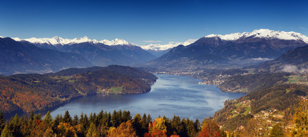 Morning autumn sunny view on Lake Millstatt in Austria, Carinthia. With small towns and villages on shores and snow-capped mountains in the background.の写真素材