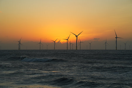 An image of windturbines in the sea at sunset.の写真素材